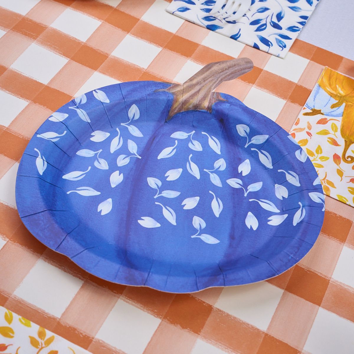 The Harvest Blues Table Setting by Sophistiplate features a blue, pumpkin-shaped designer paper plate with white leaf motifs—ideal for a charming tablescape-in-a-box.