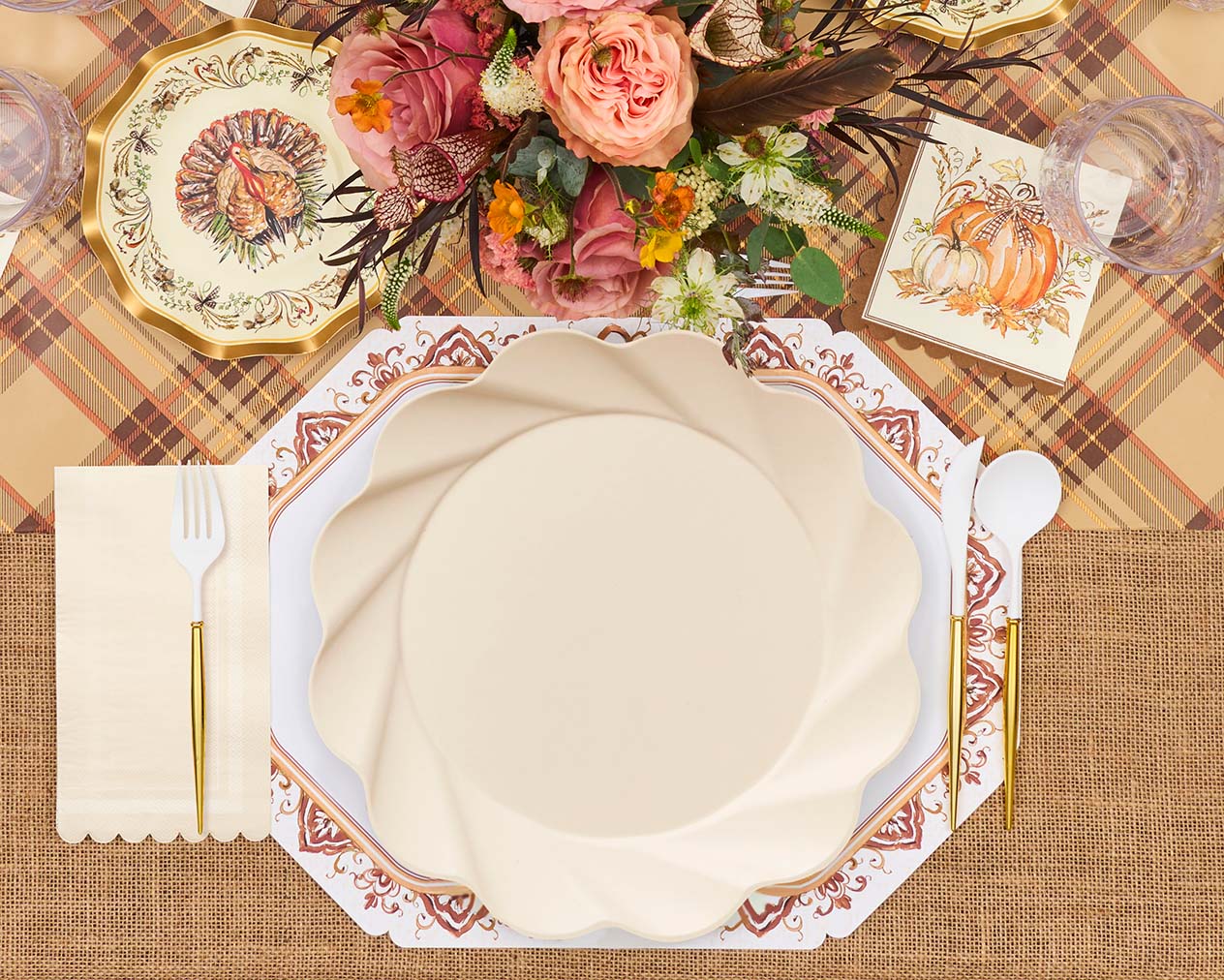 Create a festive table with Sophistiplate LLC’s Ivory Harvest: Thanksgiving Table for 16, including floral centerpieces, gold utensils, and turkey-and-pumpkin plates on a plaid cloth.