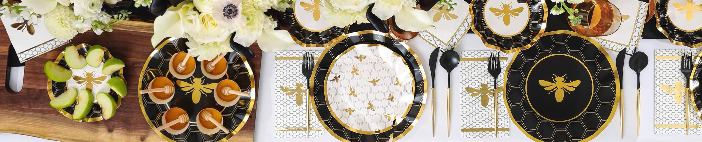 A table set with bee-themed plates, napkins, and cups in black, gold, and white, surrounded by white flowers, green apples, and caramel apple slices on a wooden serving board.