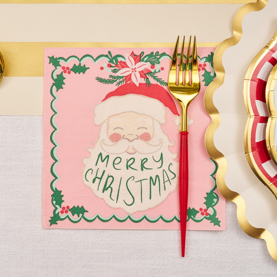 Add a touch of holiday cheer to your gatherings with the Sugarplum Tis the Season Lunch Napkins (20pk), featuring Santa’s face and “Merry Christmas” text—perfectly placed under a gold and red fork alongside a gold wavy ribbon and a festive red, gold, and white plate on your decorated table.