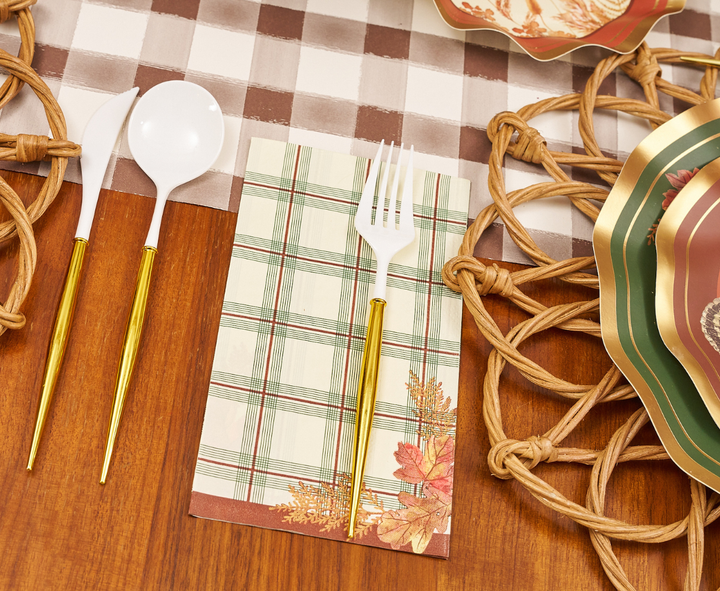 A set of Sophistiplate Woodland Harvest Guest Towels rests atop a wooden table, surrounded by decorative placemats and festive paper plates with autumn designs.
