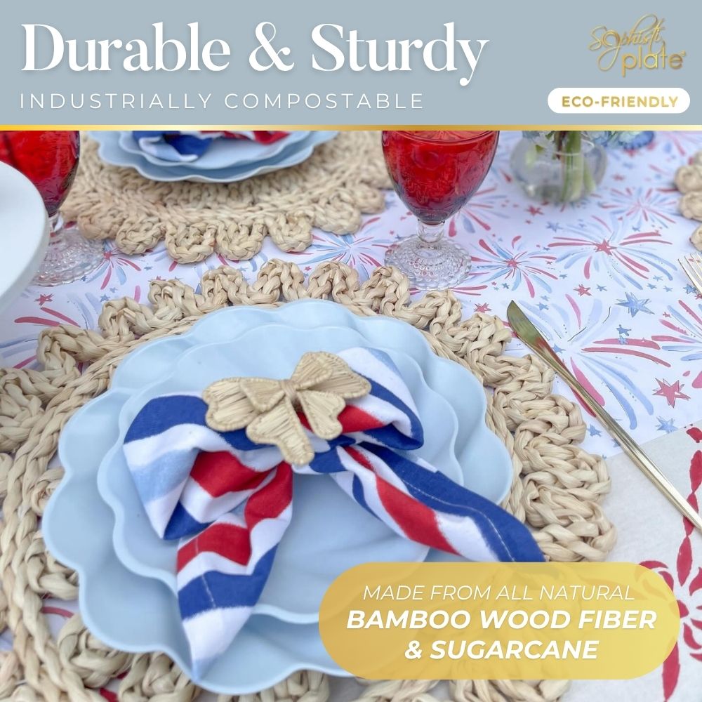 A close-up of Sophistiplate’s Eco-Friendly Table Setting- Sky Blue shows compostable party plates, a red, white, and blue napkin with a gold butterfly ring, woven placemats, and red drinks—all made from eco-friendly bamboo fiber and sugarcane.