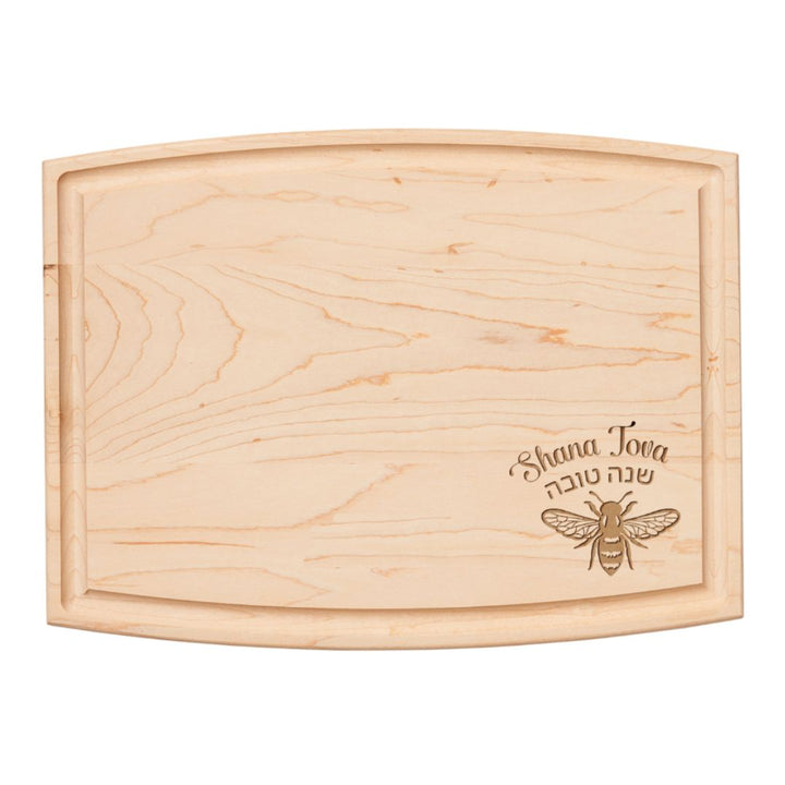 The 12" x 9" Arched Maple Board by Maple is a lightweight hard rock maple cutting board with curved edges, engraved with a bee and “Shana Tova” in English and Hebrew, ideal as a unique charcuterie board.