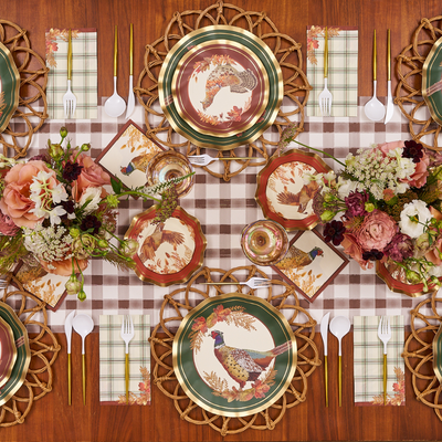 A fall-themed table setting with Sophistiplate Woodland Harvest Dinner Plates (8pk), featuring a pheasant pattern, plaid napkins, floral centerpieces, and gold utensils on a checkered table runner atop a wooden table.