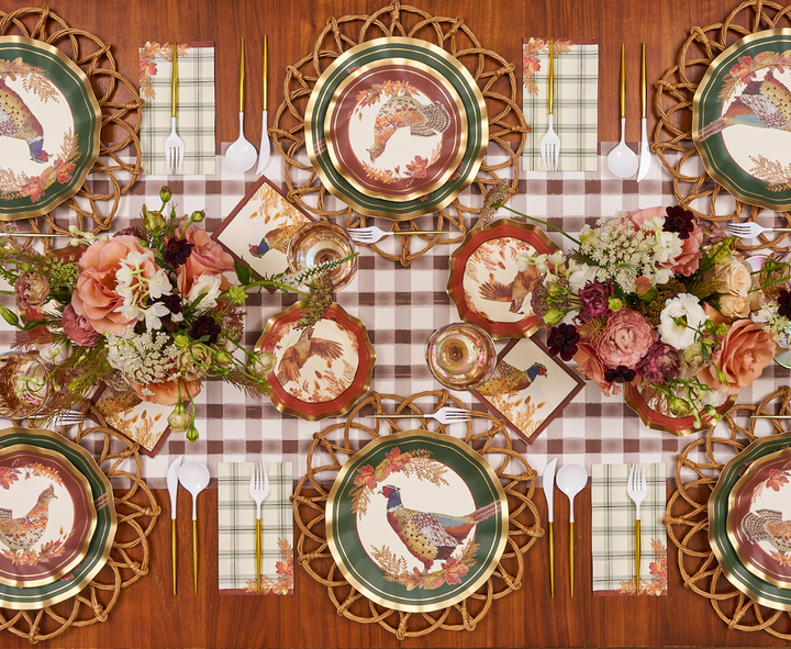 A fall-themed table setting with Sophistiplate Woodland Harvest Dinner Plates (8pk), featuring a pheasant pattern, plaid napkins, floral centerpieces, and gold utensils on a checkered table runner atop a wooden table.