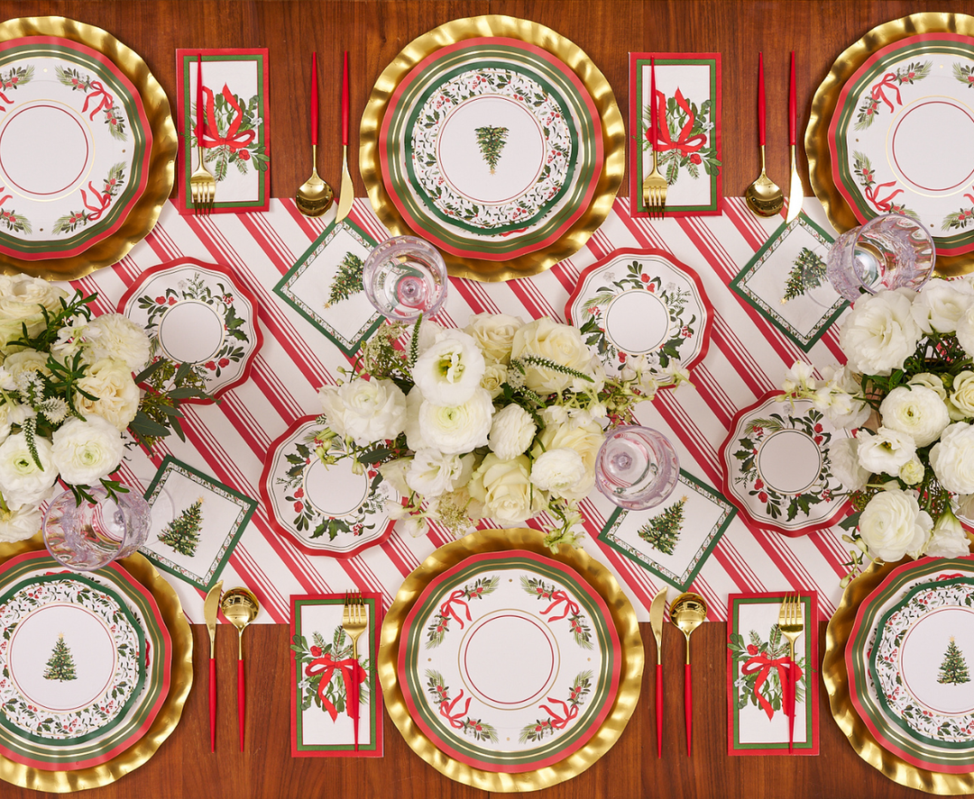 Set a festive Christmas table with gold chargers, red and white striped placemats, gold cutlery, red napkins, and elegant white floral centerpieces. For the perfect holiday touch, use Sophistiplate’s Home for the Holidays Dinner Plates (8 pack), featuring charming Christmas tree designs.