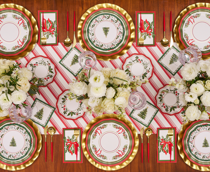 Set a festive Christmas table with gold chargers, red and white striped placemats, gold cutlery, red napkins, and elegant white floral centerpieces. For the perfect holiday touch, use Sophistiplate’s Home for the Holidays Dinner Plates (8 pack), featuring charming Christmas tree designs.