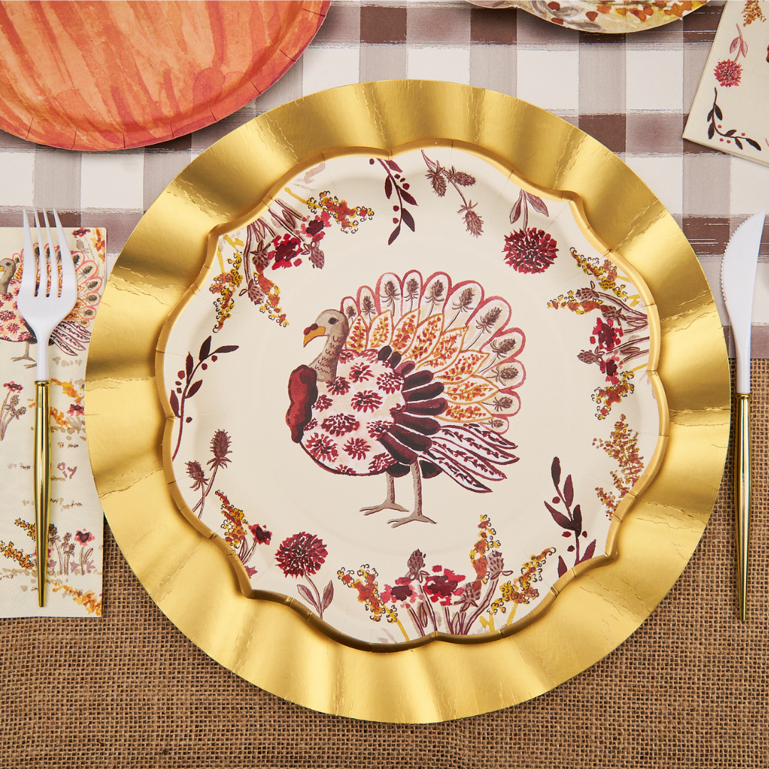 The Sophistiplate Amber Harvest Dinner Plates (8pk) feature a decorative gold scalloped edge and a vibrant turkey illustration surrounded by autumn foliage designs, set against a checkered tablecloth motif with utensils and napkins—making them the perfect festive touch for your Thanksgiving dinner or autumn party table setting.
