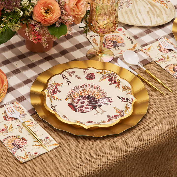 A festive table setting featuring Sophistiplate’s Amber Harvest Dinner Plates (8pk) atop a gold charger, paired with floral napkins, gold utensils, and a flower centerpiece on a plaid and burlap tablecloth.