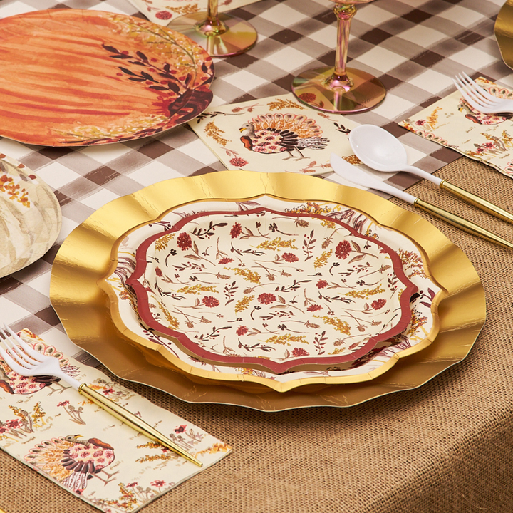 A table set with Sophistiplate Amber Harvest Salad Plates (8-pack), matching napkins, plastic utensils, and glasses atop a checkered tablecloth and burlap runner, creating an autumn-themed dining arrangement.