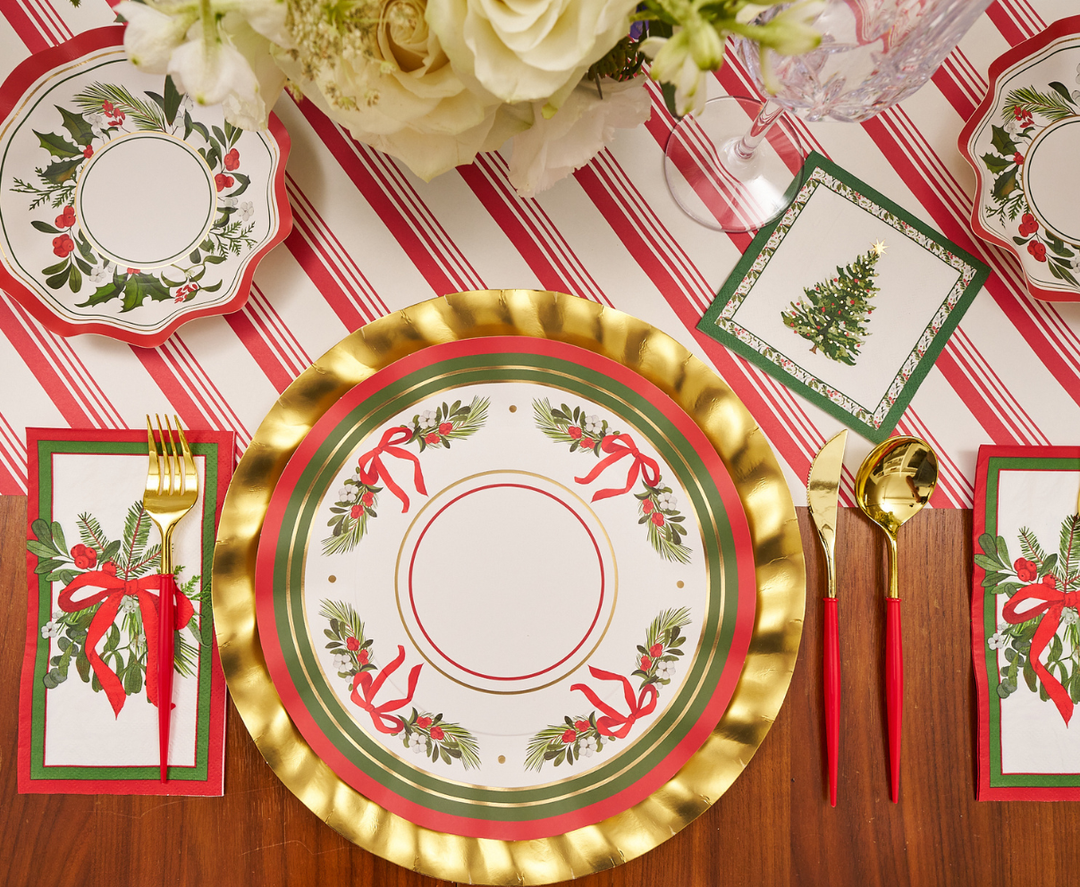 Set a festive table with gold and red utensils, holiday-themed napkins, and a centerpiece of white flowers atop a red and white striped tablecloth. Featuring the charming “Home for the Holidays” holly and ribbon design by Sophistiplate, these dinner plates (8-pack) add both convenience and cheer to your Christmas celebration.