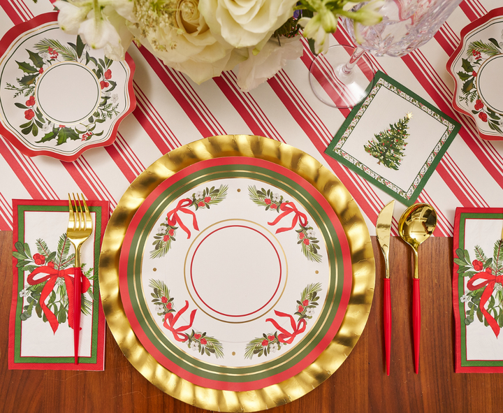 Set a festive table with gold and red utensils, holiday-themed napkins, and a centerpiece of white flowers atop a red and white striped tablecloth. Featuring the charming “Home for the Holidays” holly and ribbon design by Sophistiplate, these dinner plates (8-pack) add both convenience and cheer to your Christmas celebration.