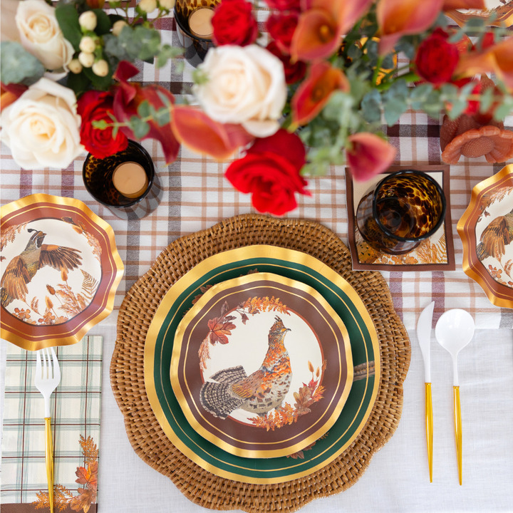 Transform your fall dining experience with the Sophistiplate Woodland Harvest Table Setting, featuring rooster-themed designer paper plates, gold-rimmed utensils, amber-hued glasses, plaid napkins, and a floral centerpiece of red, white, and peach blooms—set atop a warm-toned autumn plaid tablecloth.