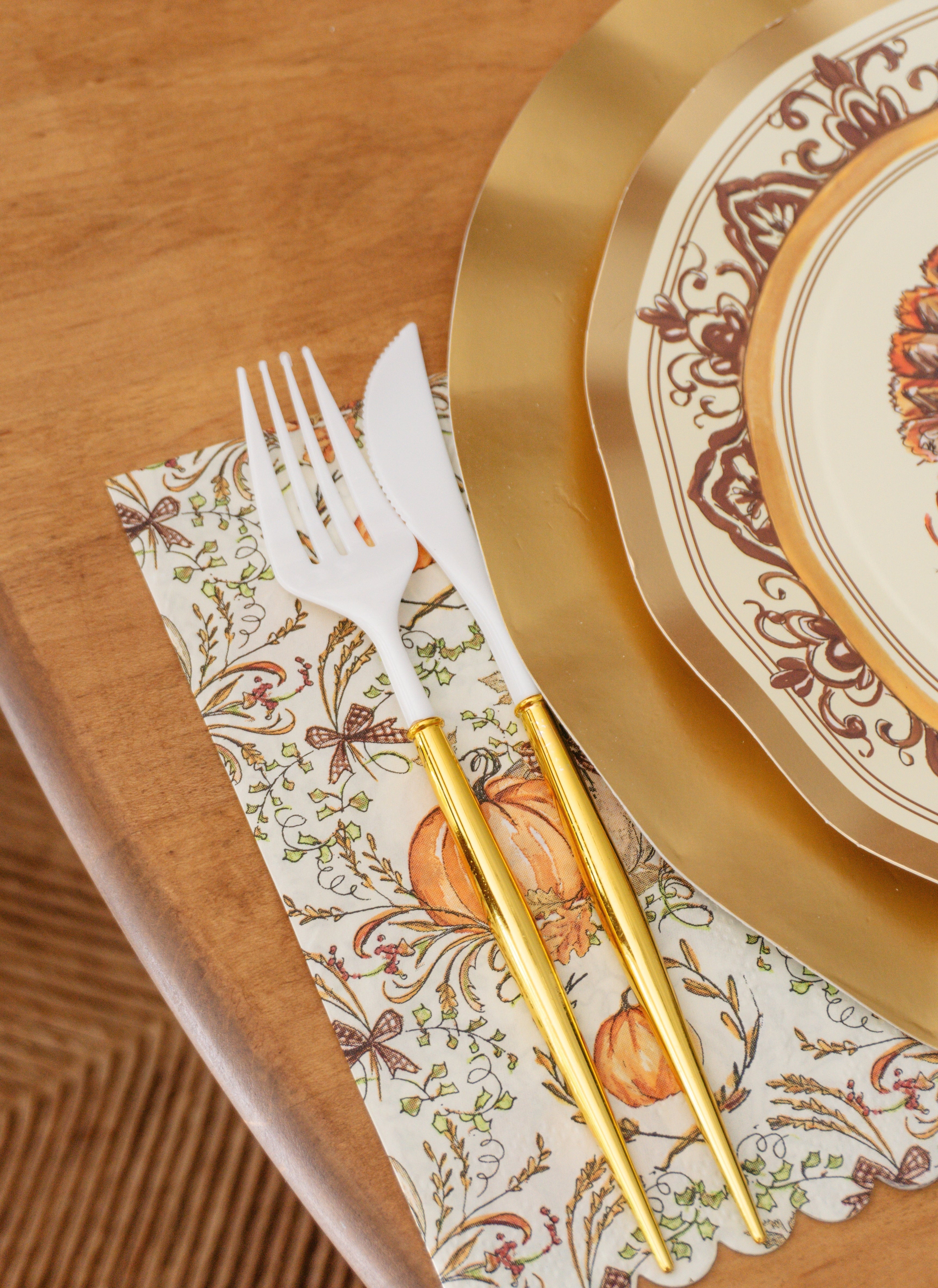 Sophistiplate Turkey & Gourds Guest Towels/20pk featuring a scalloped edge and fall pumpkin pattern, styled with a white and gold fork and knife next to a decorative plate.