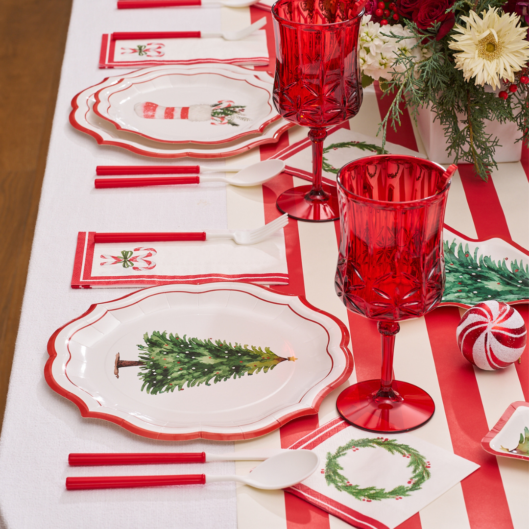 Create a festive Christmas tablescape with the Merry and Bright Table Setting by Sophistiplate, featuring red and white accents, stylish disposable plates, holiday napkins, and coasters with Christmas trees, stockings, bells, and wreath designs.