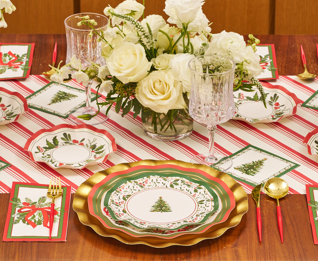 Create a cheerful holiday tablescape with gold, green, and red plates adorned with Christmas tree designs, complemented by Sophistiplate’s “Home for the Holidays” Appetizer/Dessert Bowls (8pk), which feature an elegant wavy edge for extra style. Complete the look with a white floral centerpiece, a striped table runner, and gold utensils accented with red handles.