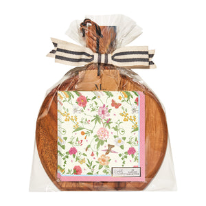 The Sophistiplate 9.75" x 8" Rococo Board Gift Kit features a round acacia wood board with a handle, packaged in clear plastic with a striped bow and includes floral-patterned cocktail napkins on the front. Spreader not included.