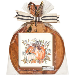 The Sophistiplate 9.75" x 8" Board Gift Kit: Turkey and Gourds features a round acacia wood board wrapped in clear plastic with a striped ribbon and a fall-themed napkin showing turkeys and gourds for an autumn touch.