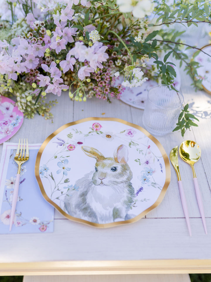 Set your table for any party-in-a-box celebration with the Charming Easter Table Setting by Sophistiplate—featuring a decorative designer disposable plate adorned with a delightful rabbit illustration surrounded by flowers, paired with gold-toned cutlery, a glass, and a floral arrangement to add an elegant touch.