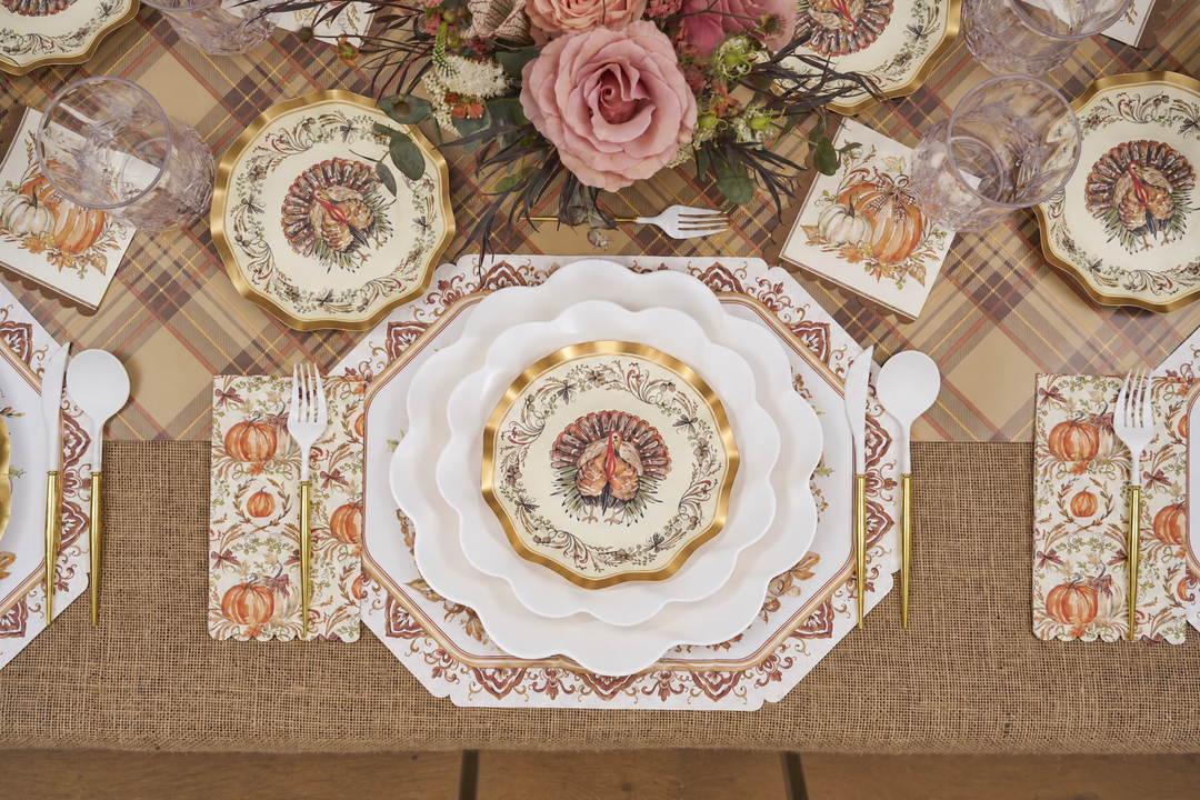 Create a Thanksgiving table setting with the Ivory Harvest Table Setting by Sophistiplate, featuring eco-friendly turkey-themed disposable plates, pumpkin napkins, elegant glassware, and a floral centerpiece with pink roses—all beautifully arranged on a plaid tablecloth and rustic burlap runner.