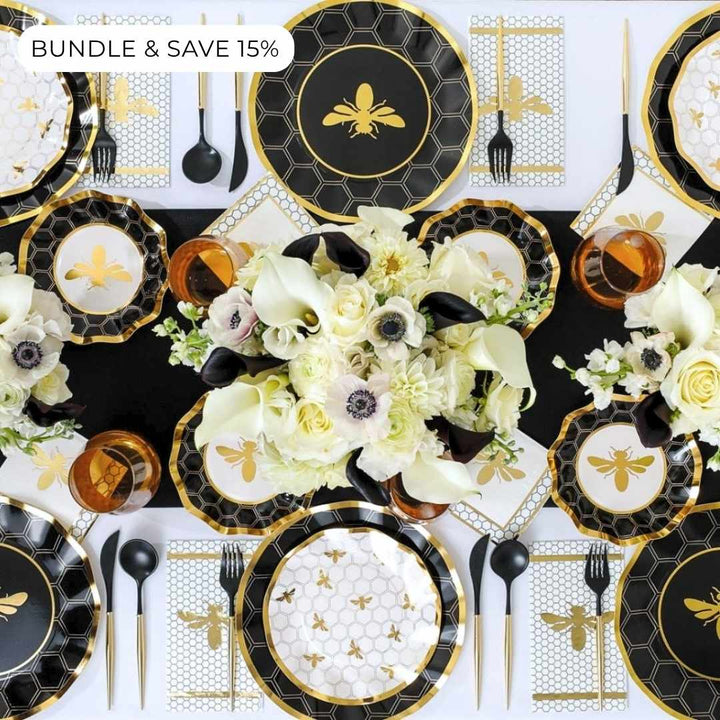 The Sophistiplate Rosh Tablescape for 16 Guests: Honeybee features elegant black, gold, and white bee-themed heavy duty paper plates, cups, and napkins. Set on a table with floral centerpieces of white flowers and calla lilies, it’s the perfect choice for a stylish Rosh Hashanah celebration. Text in the corner reads: BUNDLE & SAVE 15%.