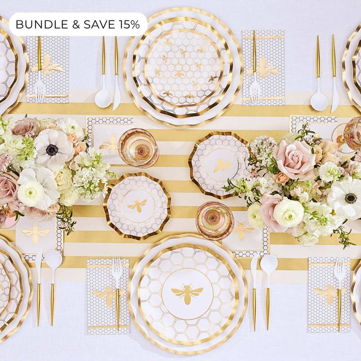 Bundle & Save 15% (label in upper left corner) Create a stylish Rosh Hashanah table setting with the “Rosh Tablescape for 16 Guests: White Honeybee” by Sophistiplate LLC, featuring elegant gold honeybee-themed designer disposable plates, coordinating gold utensils, floral centerpieces, and a chic gold-and-white striped table runner.