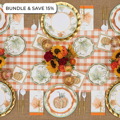 Overhead view of a Bright & Thankful: Thanksgiving Table for 16 set with autumn-themed paper plates, gold-rimmed chargers, gold cutlery, and a centerpiece of sunflowers and roses.