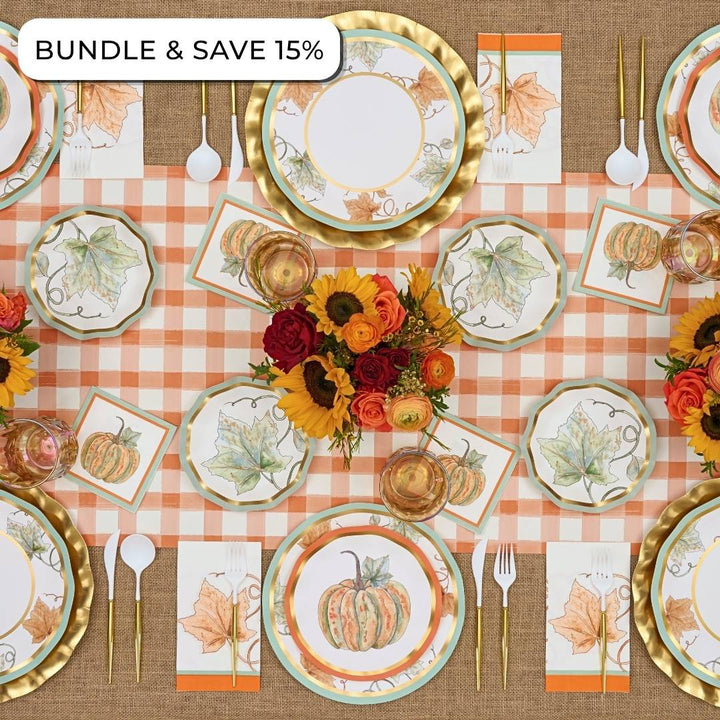 Overhead view of a Bright & Thankful: Thanksgiving Table for 16 set with autumn-themed paper plates, gold-rimmed chargers, gold cutlery, and a centerpiece of sunflowers and roses.
