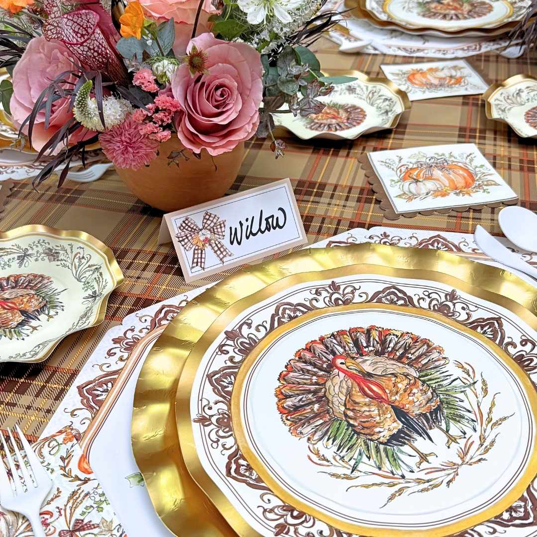 A Turkey & Gourds: Thanksgiving Table for 16 setting featuring heavy duty paper plates with gold rims and a turkey illustration, complemented by a floral centerpiece and a place card labeled Willow.