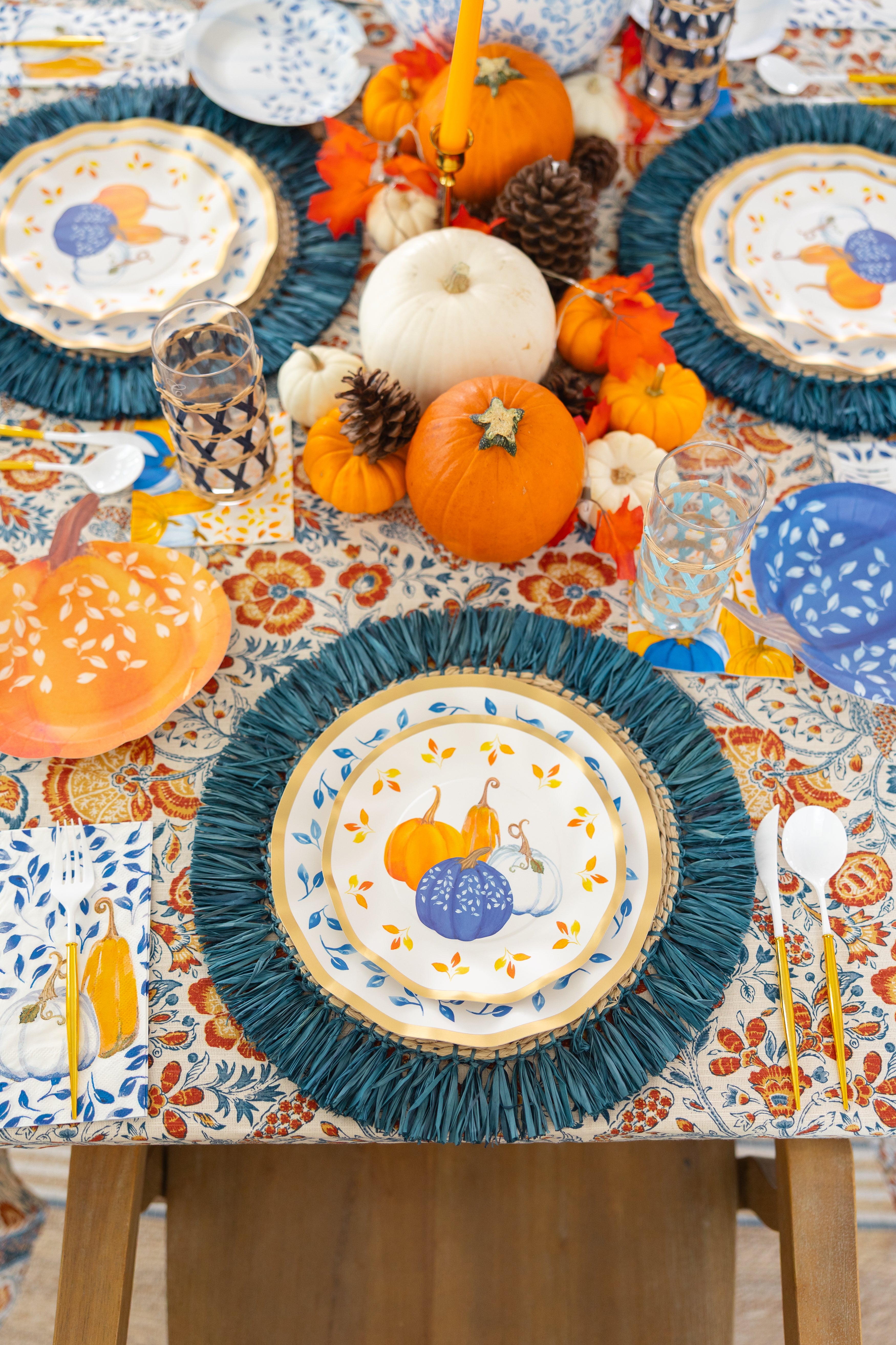 Sophistiplate's Harvest Blues Table Setting is a festive autumn tablescape-in-a-box with designer gourd paper plates, mini pumpkins, pinecones, fall leaves, a patterned cloth, and blue disposable tableware placemats.