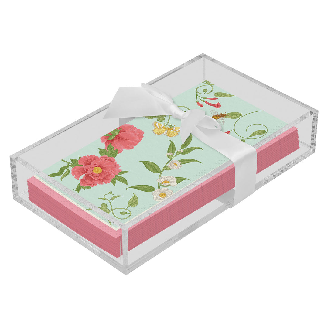 The Sophistiplate Floral Guest Towel with Napkin Tray displays pink floral napkins neatly arranged in a clear holder, topped with a white satin ribbon bow.