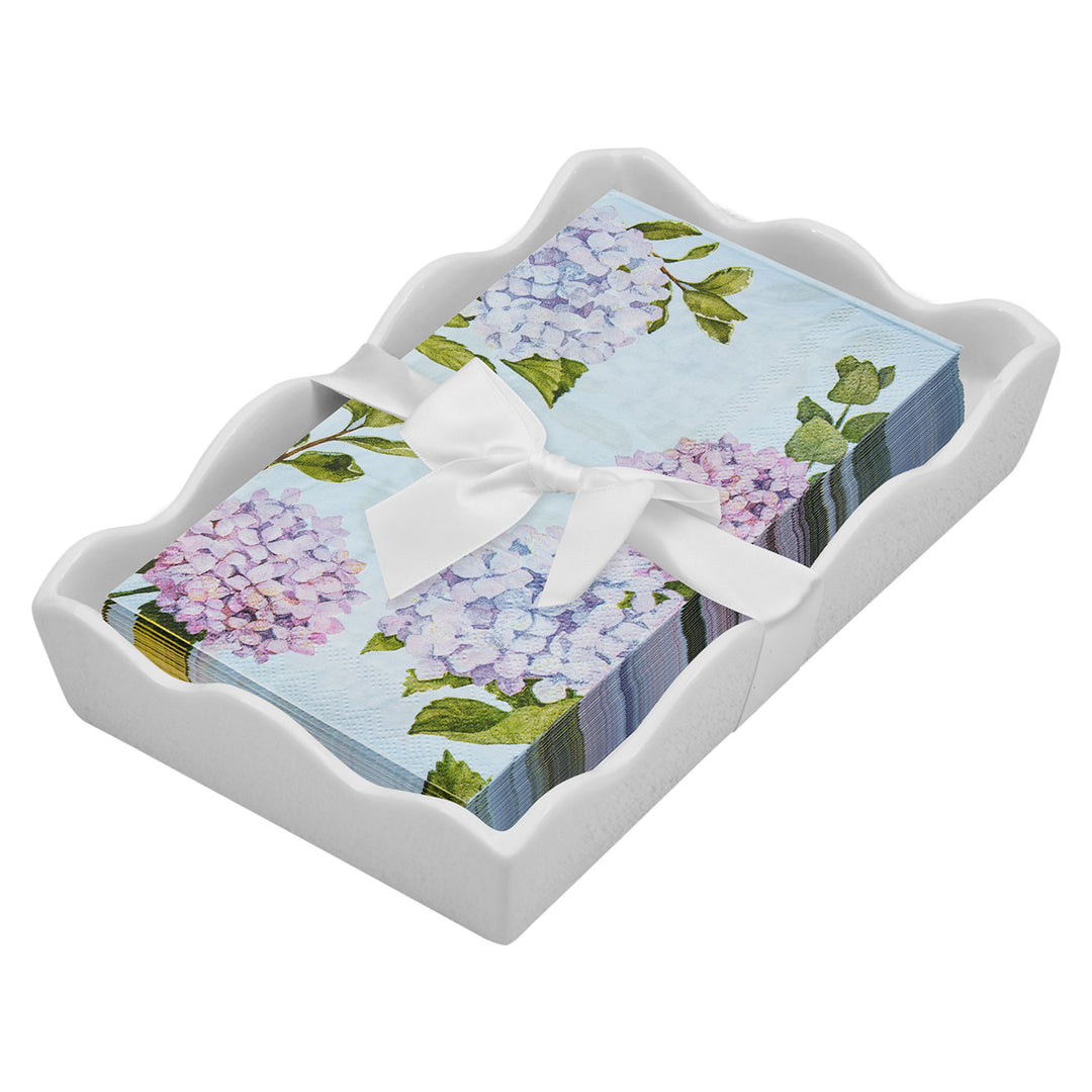 The Sophistiplate Floral Guest Towel with Napkin Tray features pastel hydrangea napkins with green leaves, elegantly tied with a white ribbon and displayed in a wavy-edged ceramic tray.