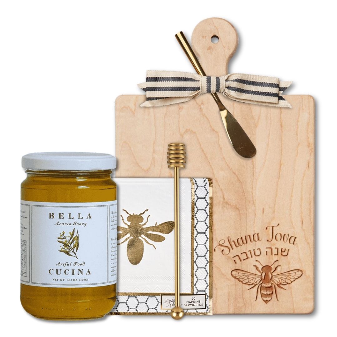 Introducing the Shana Tova Serving Set by Sophistiplate LLC: a beautifully arranged Rosh Hashanah gift featuring a wooden board adorned with “Shana Tova” in English and Hebrew, a decorative bow, a honey jar with dipper, honeycomb-patterned napkins, and charming bee-themed accents.