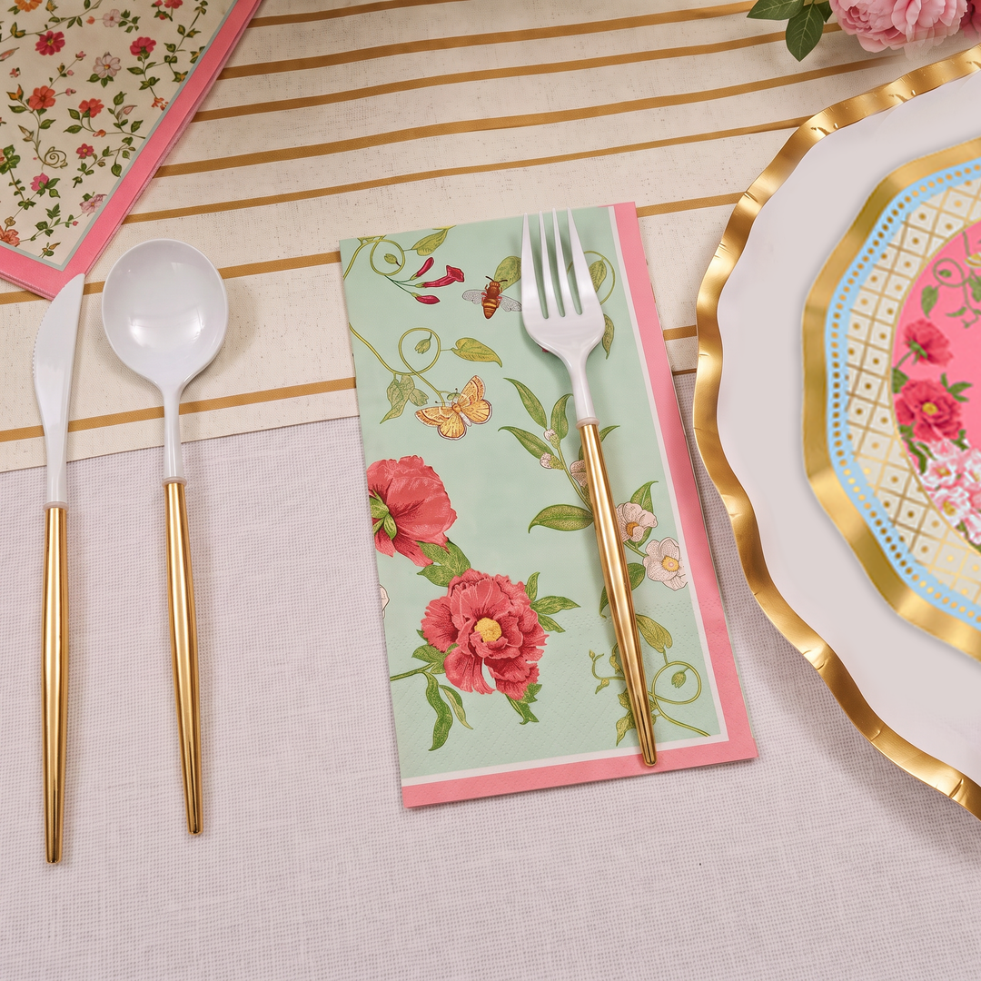 Experience the elegance of the Ivory Rococo Table Setting by Sophistiplate, featuring a neatly arranged cream-striped tablecloth, a floral napkin, gold-handled fork and spoon, a decorative designer disposable plate with a gold rim, and a pink floral heavy duty paper plate.
