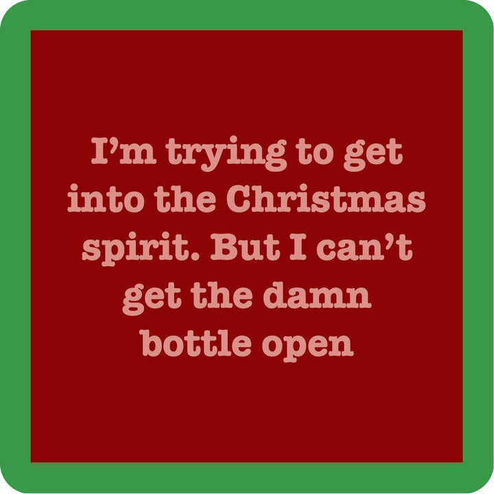 A red square coaster from Drinks On Me features beige text: “I’m trying to get into the Christmas spirit. But I can’t get the damn bottle open”—a funny Bottle Open Coaster for your bar cart or as a cheerful drink accessory.