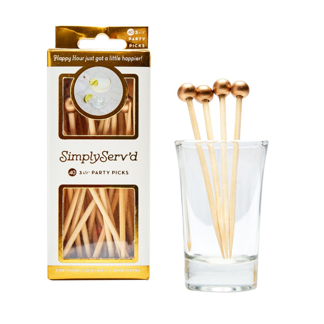 A box of Simply Serv'd Gold 3.5" Wood Party Pick/40pk sits beside a glass holding several compostable picks with metallic gold ball ends—perfect for adding style to cocktails and appetizers.
